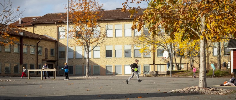 Barn som leker på skolgården och Norrtullskolan i bakgrunden.
