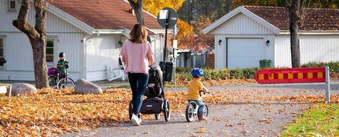 Bild: mamma som promenerar sina barn i ett villakvarter