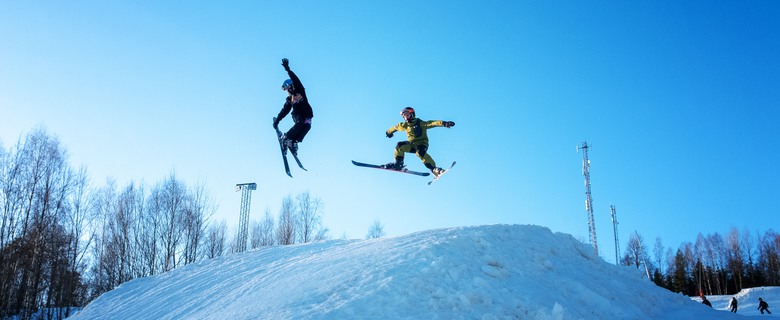 Två ungdomar som hoppar med skidor i Valbacken.