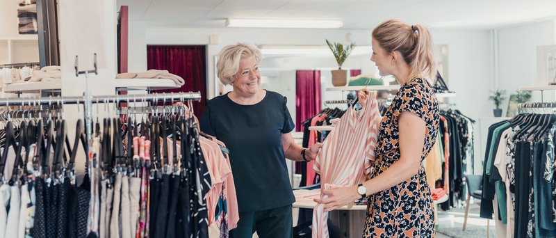 Två personer i en klädesbutik i Eksjö visar upp ett klädesplagg.