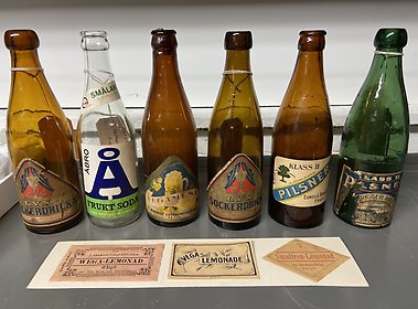 En samling flaskor för läsk och öl från Eksjöbryggerier. Från Eksjö museums samlingar.